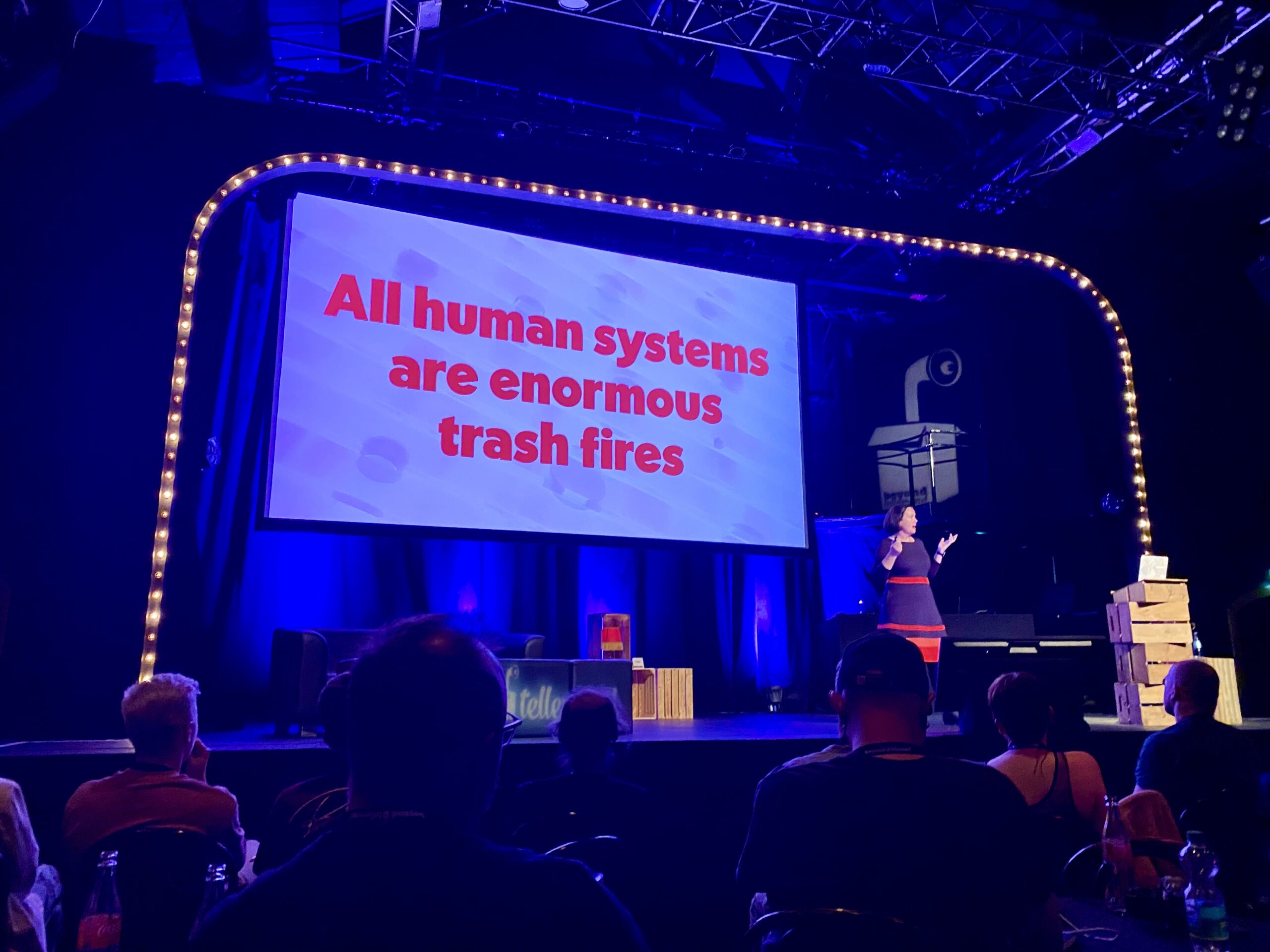 Presentation slide by Sacha Judd with text in which it reads "All human systems are trash fire"